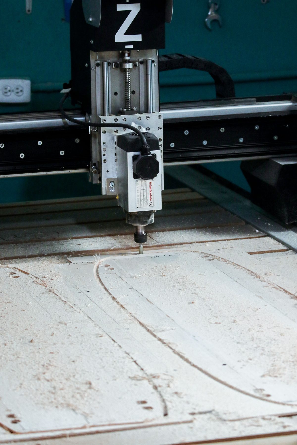 CNC router tracing a profile outline on a timber sheet